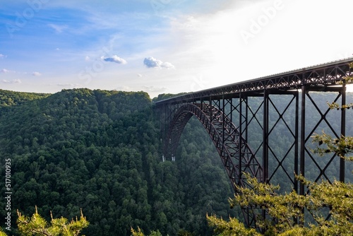 Fényképezés Angle shot of New River Gorge Bridge under the beautiful sky with green forest i