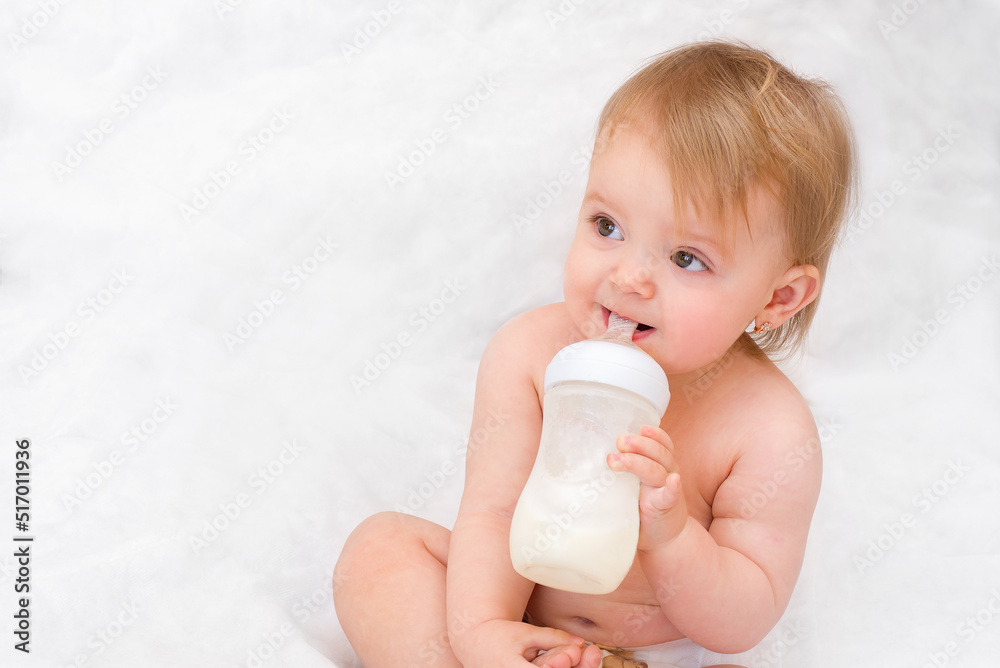Artificial feed. Happy toddler girl drinks milk from a bottle. Baby food. Artificial feed. Happy toddler girl drinks milk from a bottle. Baby food.