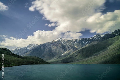 Breathtaking view of Chandra Taal surrounded by green snowcap mountains in India photo