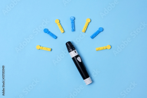 Diabetes concept on blue background. An abstract clock made of interchangeable needles and a lancet for blood sugar testing. photo