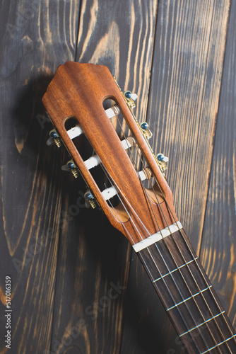 Close up neck of the guitar..Brown colored wooden guitar on the wooden background. Musical Instrument. photo