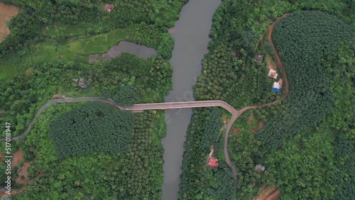 Fotografía Mesmerizing view of a river surrounded by dense green forest and a bridge over t