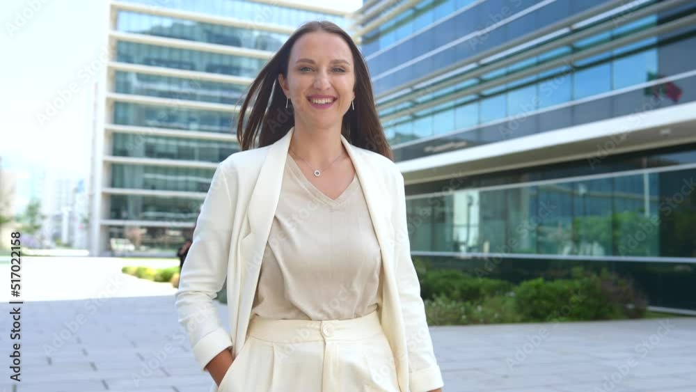 Cheerful young businesswoman in smart casual wear walking down the city street outdoors. Positive female employee taking a break from office work. Cheerful young businesswoman in smart casual wear walking down the city street outdoors. Positive female employee taking a break from office work.