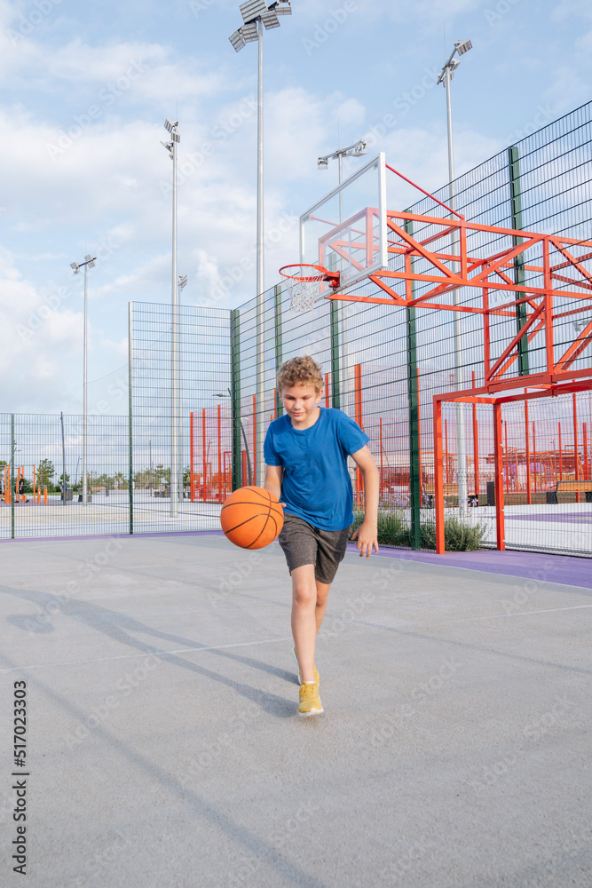 A boy is playing basketball on the playground. A boy is playing basketball on the playground.