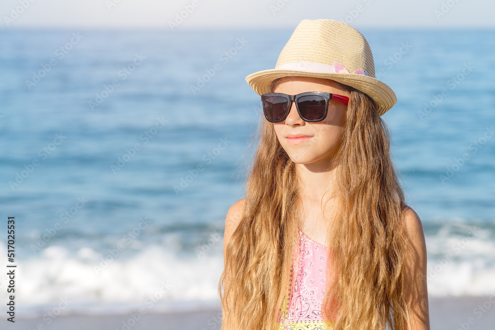 The head of a girl in a hat and glasses against the background of the sea and blue sky. The head of a girl in a hat and glasses against the background of the sea and blue sky.