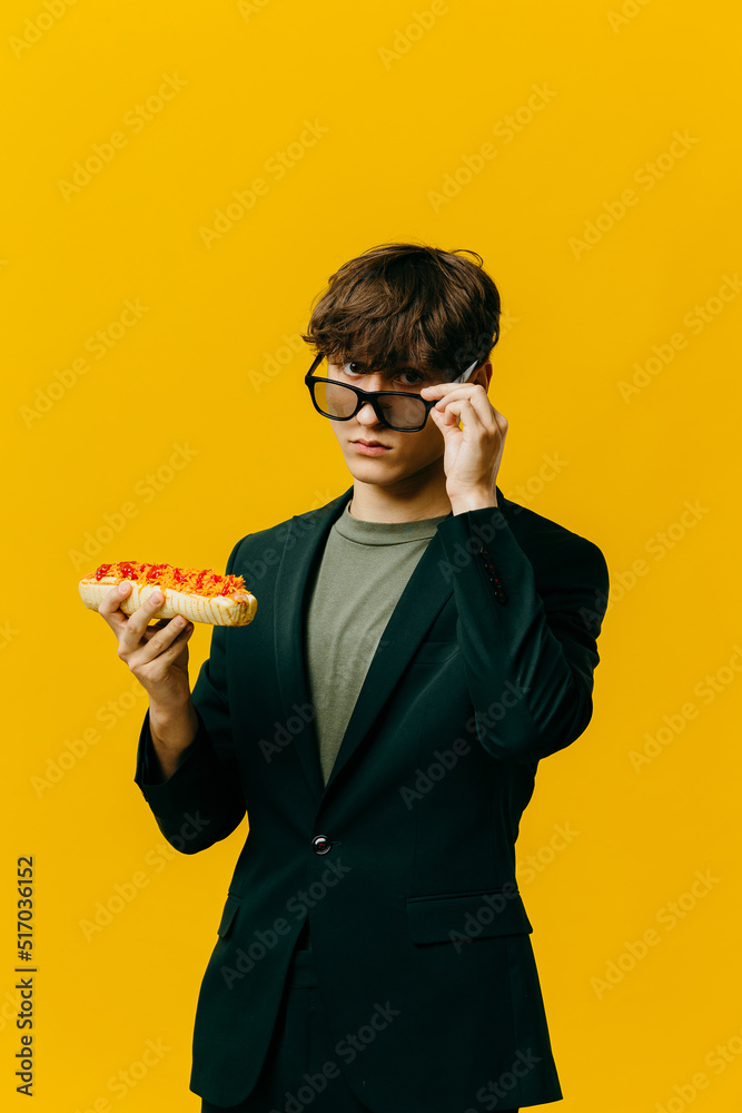 Handsome stylish young man posing on colored background with hotdog. Handsome stylish young man posing on colored background with hotdog.