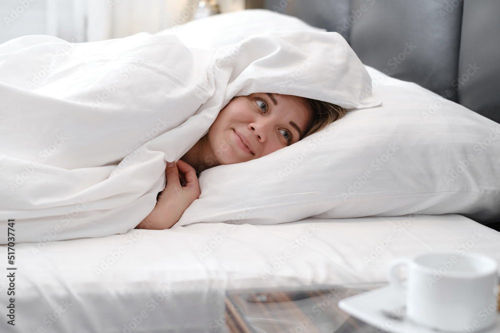 Woman covered with blanket in the morning in bed. Woman waking up from sleep in the morning. woman lying in bed and keeping eyes opened while covered with blanket. Woman covered with blanket in the morning in bed. Woman waking up from sleep in the morning. woman lying in bed and keeping eyes opened while covered with blanket.