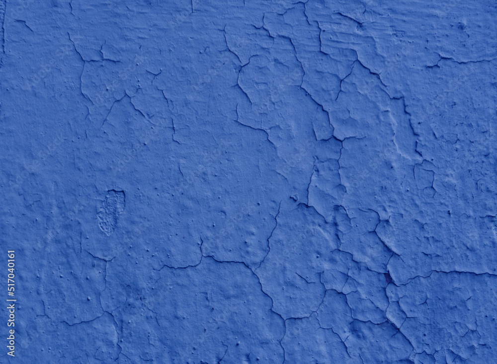 Fragment of wall covered with old damaged blue plaster.