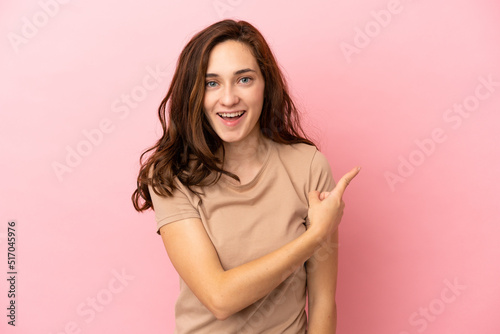 Young caucasian woman isolated on pink background surprised and pointing side © luismolinero
