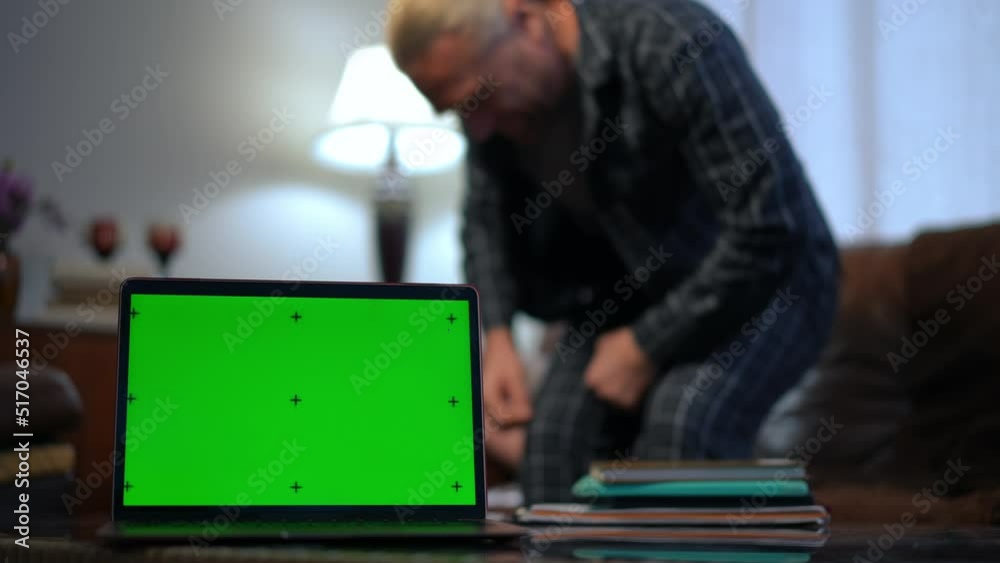 Chromakey laptop in living room with blurred Caucasian man entering