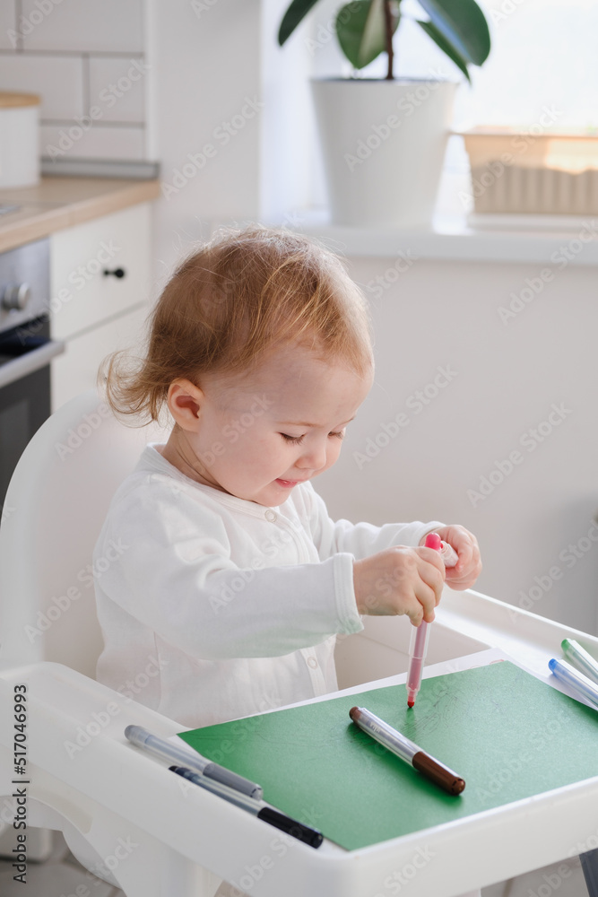 Close up portarit of a baby toddler drawing his first scribbles using colored felt-tip pens. Drawing development in kids. Close up portarit of a baby toddler drawing his first scribbles using colored felt-tip pens. Drawing development in kids.