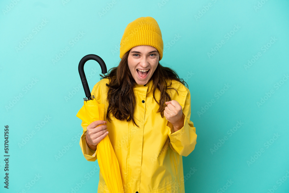 Young caucasian man holding an umbrella isolated on blue background celebrating a victory in winner position Young caucasian man holding an umbrella isolated on blue background celebrating a victory in winner position