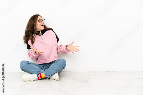 Young caucasian woman sitting on the floor isolated on white background with surprise facial expression © luismolinero