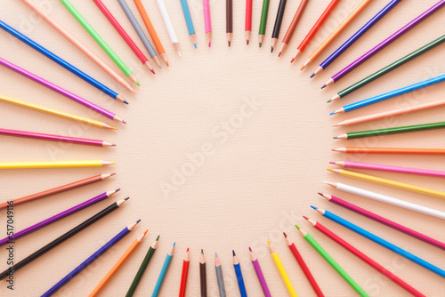 Color pencils in circle composition on the beige background, colorful abstract card with copy space
