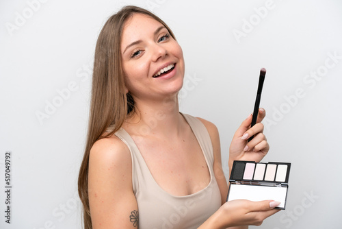 Young Lithuanian woman isolated on white background with makeup palette and happy