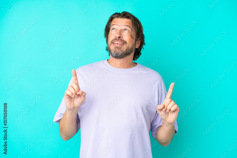 Senior dutch man isolated on blue background surprised and pointing up Senior dutch man isolated on blue background surprised and pointing up