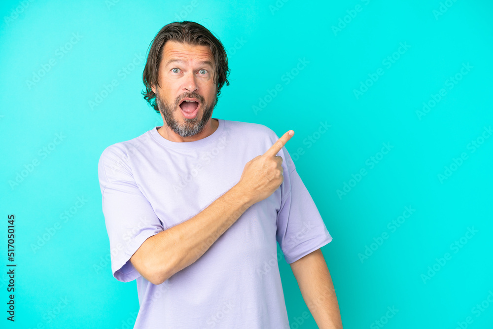 Senior dutch man isolated on blue background surprised and pointing side Senior dutch man isolated on blue background surprised and pointing side
