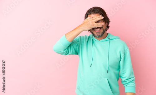 Senior dutch man isolated on pink background covering eyes by hands and smiling © luismolinero