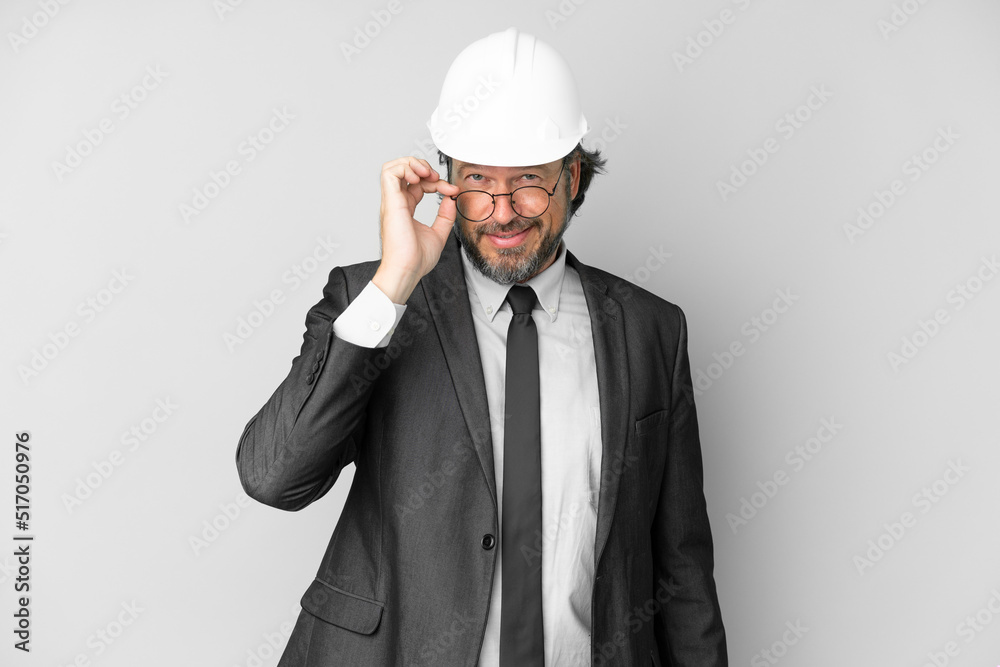 Young architect man with helmet over isolated background with glasses and happy Young architect man with helmet over isolated background with glasses and happy