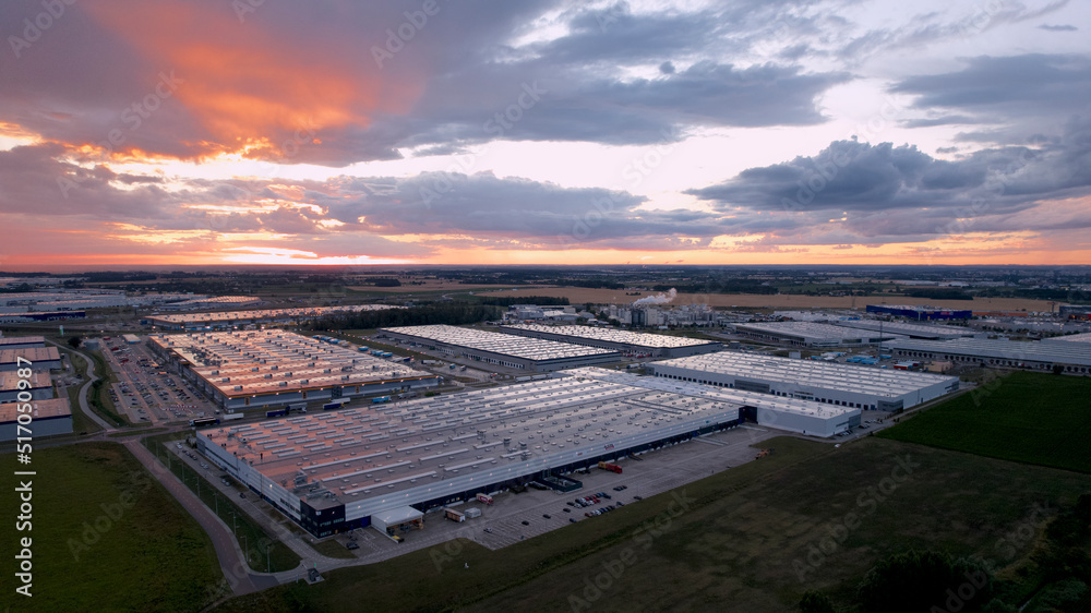 ogromne magazyny centra logistyczne o zachodzie słońca z drona
