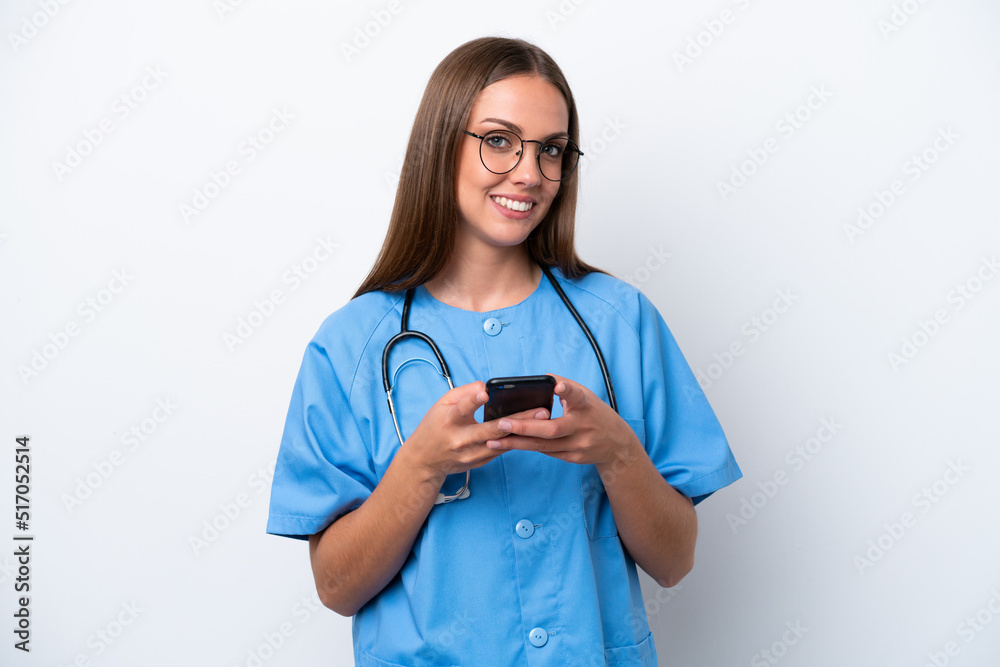 Young nurse caucasian woman isolated on white background sending a message with the mobile Young nurse caucasian woman isolated on white background sending a message with the mobile