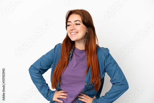 Young redhead woman isolated on white background posing with arms at hip and smiling