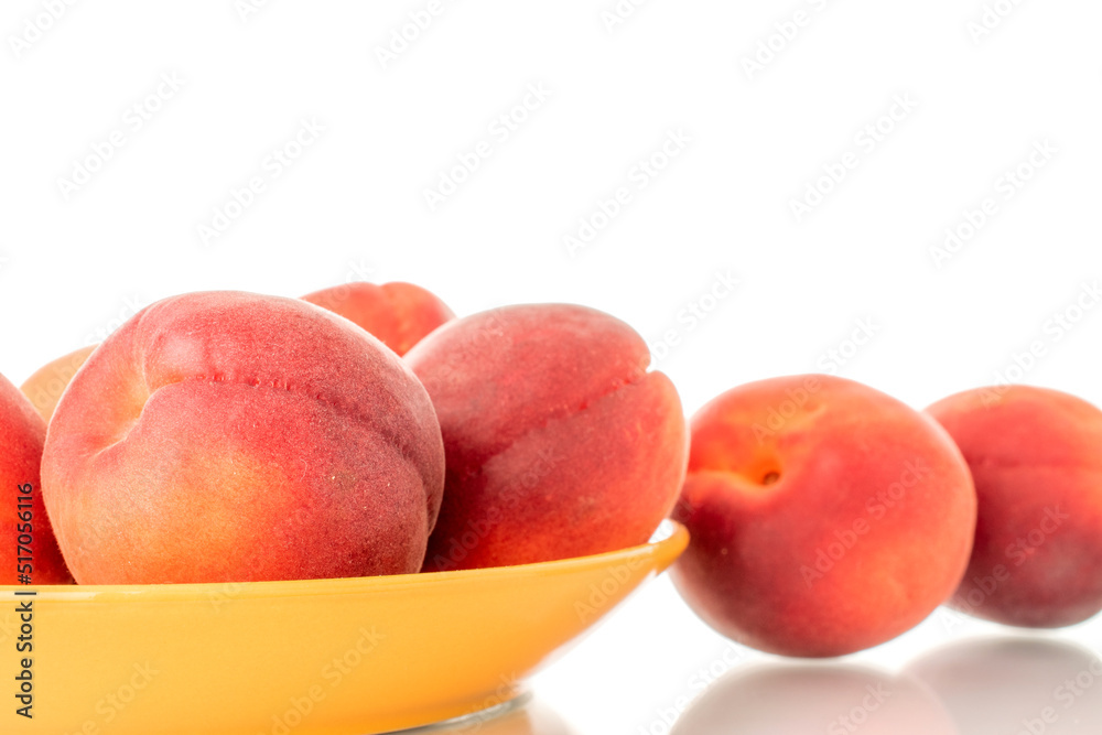 Several ripe red apricots on a yellow ceramic saucer, close-up, isolated on a white background. Several ripe red apricots on a yellow ceramic saucer, close-up, isolated on a white background.