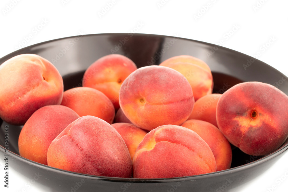 Several ripe red apricots on a black ceramic plate, close-up, isolated on a white background. Several ripe red apricots on a black ceramic plate, close-up, isolated on a white background.