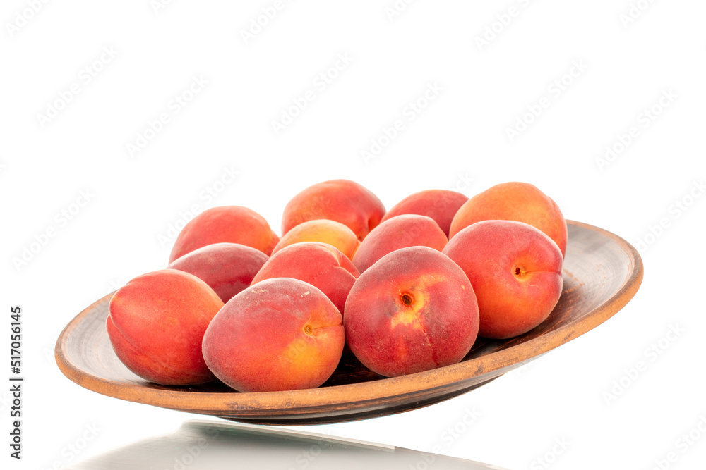 Several ripe red apricots on a clay dish, close-up, isolated on a white background. Several ripe red apricots on a clay dish, close-up, isolated on a white background.