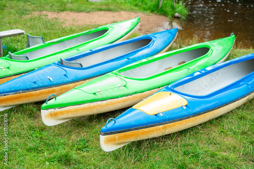 Colorful boats on green grass, kayak on the lake