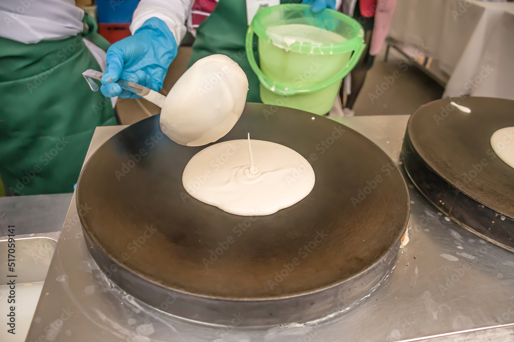 Obraz premium Making Russian pancakes with filling on an industrial scale in a cafe.