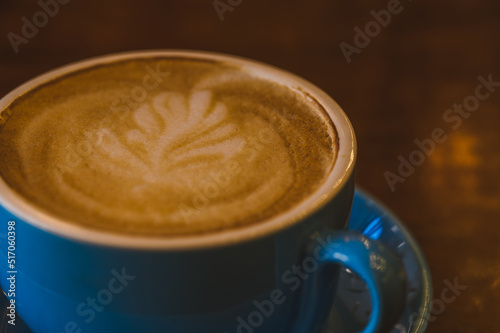 A blue cappuccino mug with a petal pattern on the foam. Minimalistic coffee mug concept.