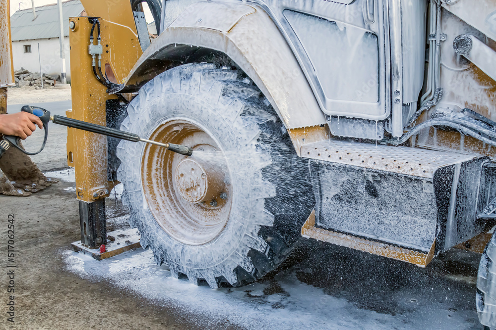 Washing a wheeled tractor at a car wash with a foam solution foto de