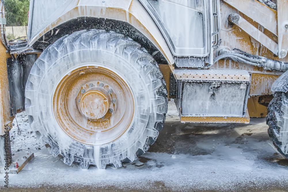 Washing a wheeled tractor at a car wash with a foam solution Stock