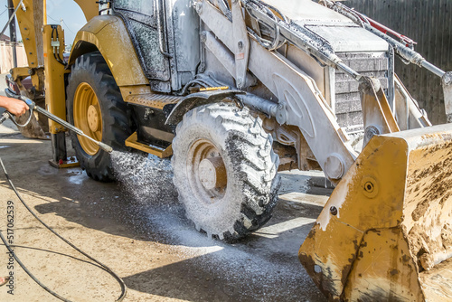 Washing a wheeled tractor at a car wash with a foam solution