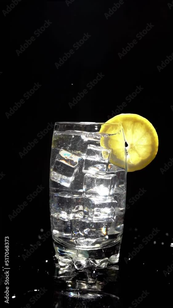 Slow motion splash of an ice cube in a glass of fizzy drink decorated ...