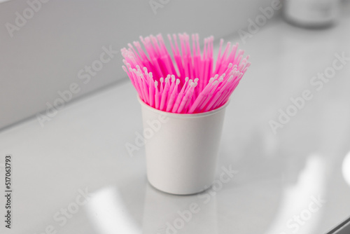 Eyelash microbrush applicators. Pink microbrushes in a glass. Consumables. Microbrushes are used in the beauty industry and dentistry photo