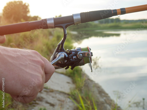 Obraz na plátně Fishing rod wheel closeup, man fishing on the lake