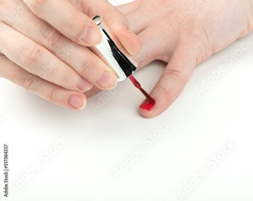 A young woman applies polish on her pinky nail.