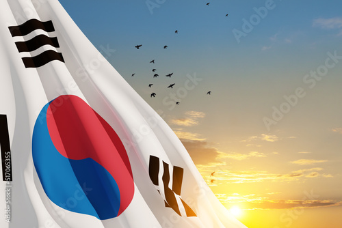 Waving South Korea flag on sunset sky with flying birds. Background with place for your text. 3d-rendering.