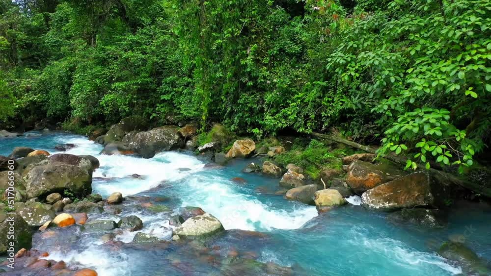 Turquoise river with mossy rocks in tropical forest