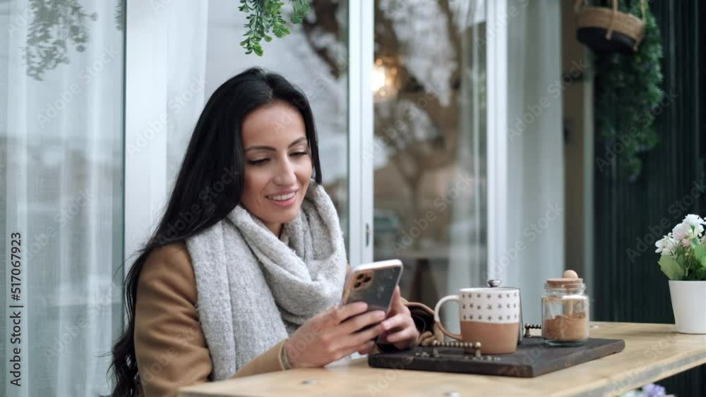 Video of beautiful stylish woman sending messages with smartphone while having breakfast sitting in the eco bar terrace. Video of beautiful stylish woman sending messages with smartphone while having breakfast sitting in the eco bar terrace.
