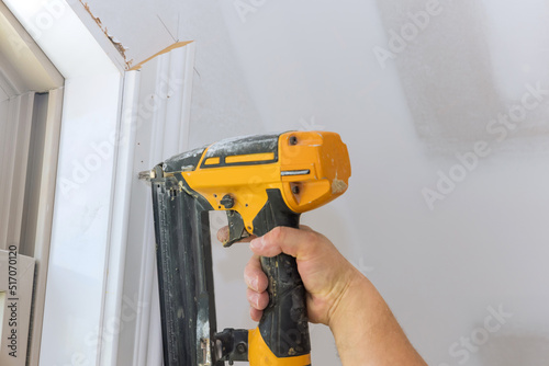 In our new home, a carpenter uses a brad nail gun to nail the casings molding trim to the walls