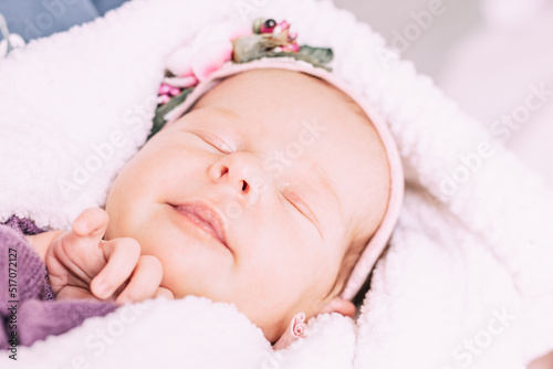 Sleeping newborn baby girl on a white fluffy soft blanket. First month