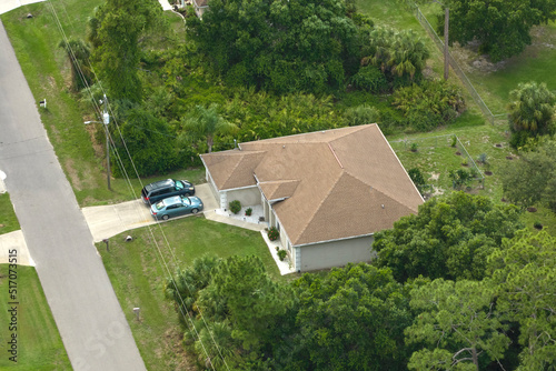 Aerial view of typical contemporary american private house with roof top covered with asphalt shingles and green lawn on yard