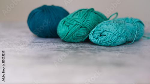  Green and blue yarn balls on gray background. Knitting yarn for handmade summer and autumn clothes. Natural wool or cotton background. place for text and copy space. selective focus