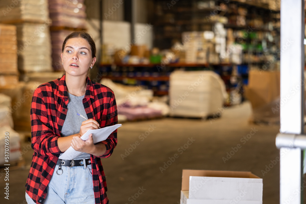 Obraz premium Female manager leads the accounting of materials in a large warehouse