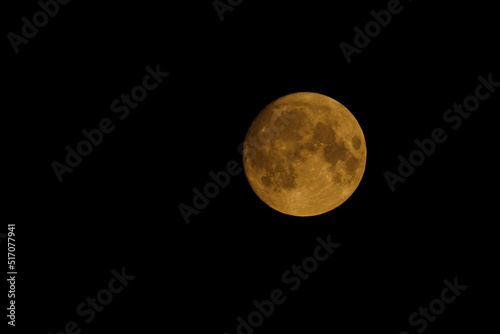 full moon in the night sky, Super Moon, amber with craters in the black sky, isolated