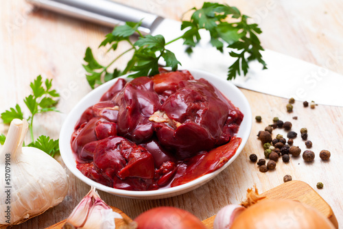 Ingredients for cooking. Raw chicken liver with onion, garlic, spices and herbs on wooden table