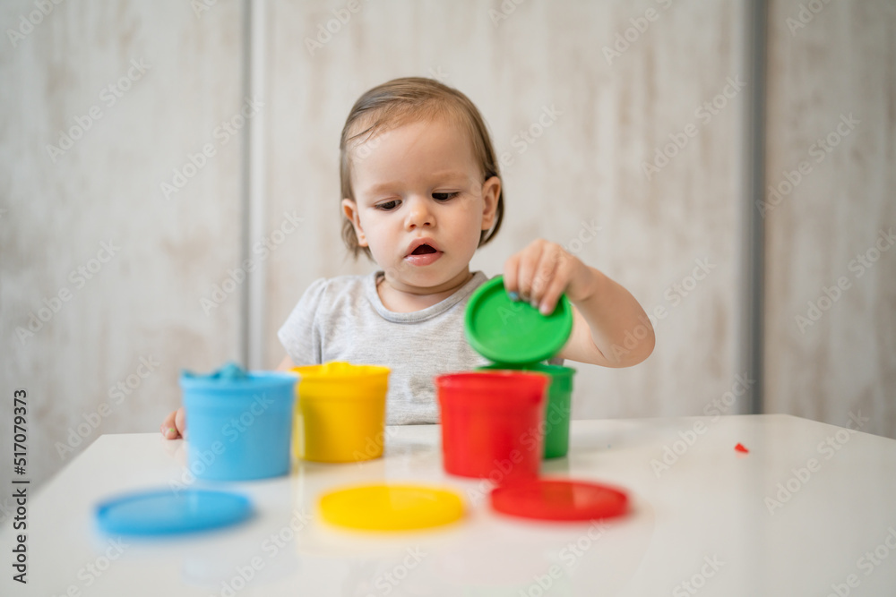 One girl small caucasian toddler child playing with colorful plasticine on the table at home alone childhood and growing up concept copy space One girl small caucasian toddler child playing with colorful plasticine on the table at home alone childhood and growing up concept copy space